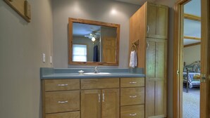 A bathroom with wooden cabinets, a sink, and a large mirror. - North Georgia Cabin, Sleeps 8, Pet Friendly (Morganton)