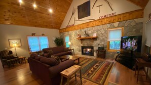 A cozy living room with a stone fireplace, wooden ceiling, and a television. - North Georgia Cabin, Sleeps 8, Pet Friendly (Morganton)
