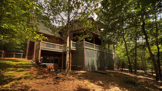 A rustic cabin with a deck, surrounded by dense trees. - North Georgia Cabin, Sleeps 8, Pet Friendly (Morganton)