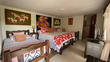 A hotel room with two beds, a desk with a computer, and floral artwork on the walls.