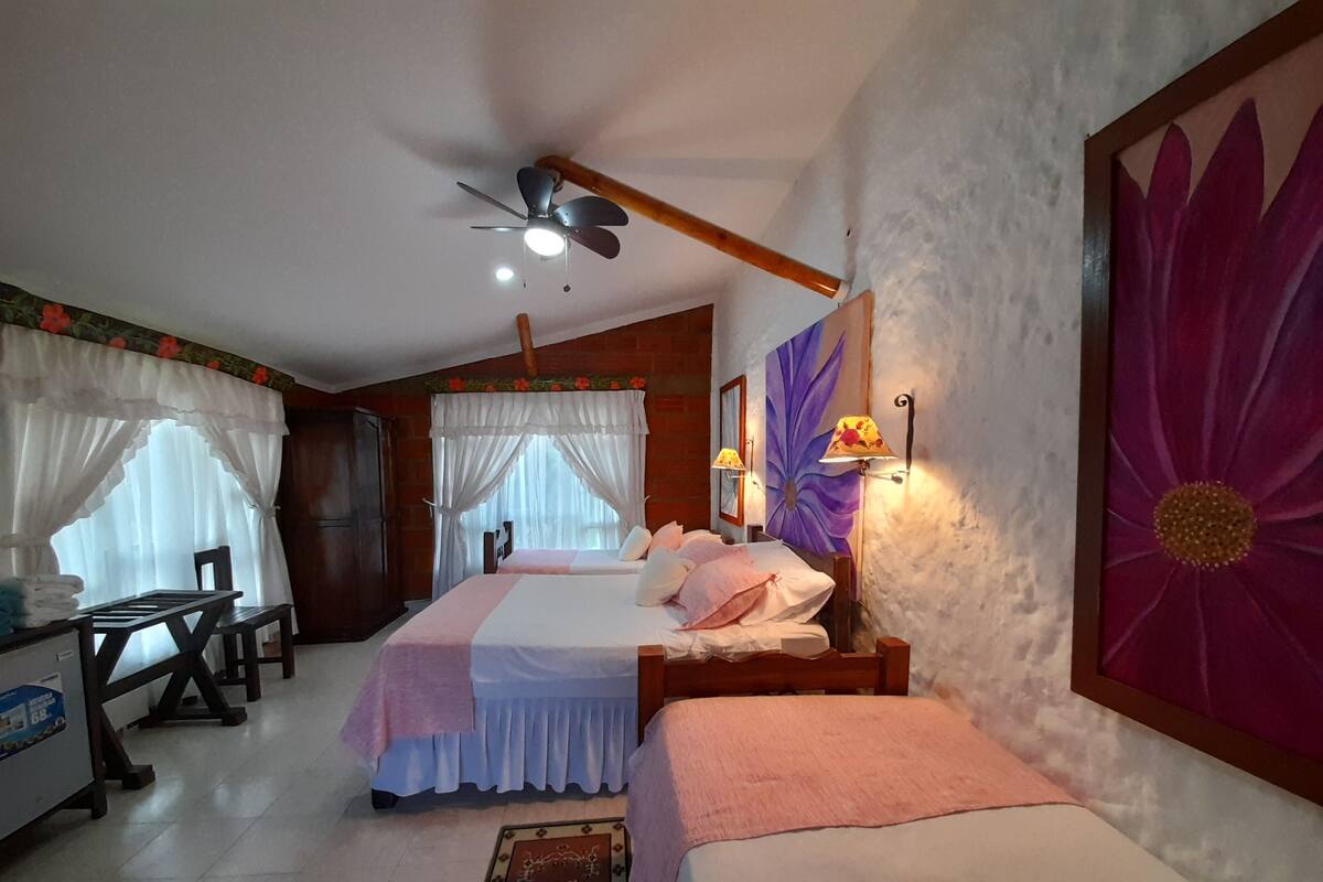 Ein Schlafzimmer mit zwei Betten, einem Deckenventilator, einem Schreibtisch und einem Stuhl.