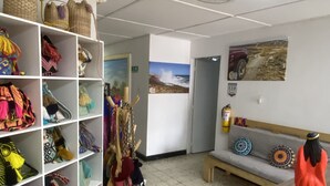 Une pièce avec un plafond blanc, un ventilateur de plafond, un comptoir d’accueil en bois et un mur orné d’un tableau.