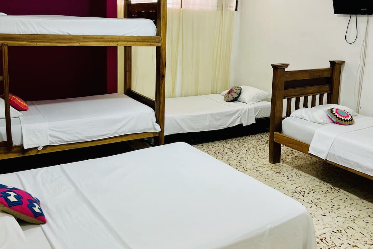 A dormitory room with bunk beds, a television, and an air conditioning unit.