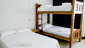 Une chambre avec un lit superposé, deux lits, une table de chevet et une petite table.