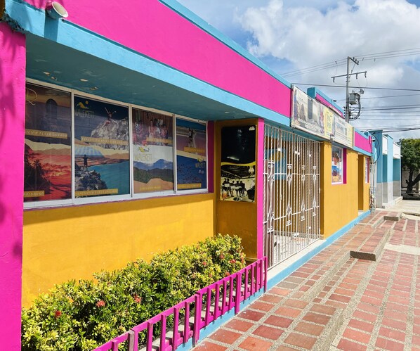 A brightly colored building with a yellow facade and pink and blue trim.