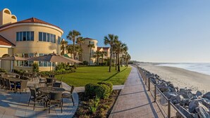 A beachfront property with a patio area, a pathway leading to the beach, and a view of the ocean. - Beautiful, First Floor South Villa at King & Prince with Resort Amenities (St Simons Island)