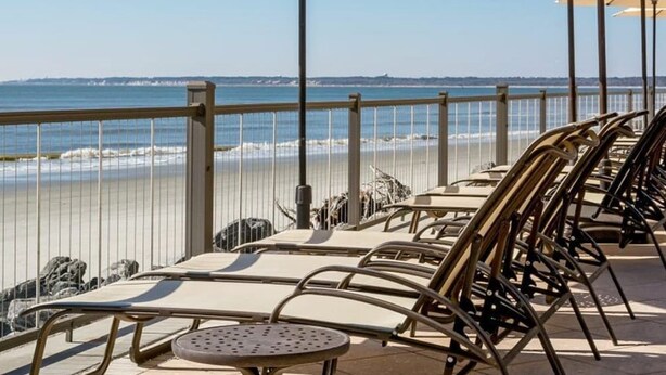 A beachside patio with lounge chairs and umbrellas, overlooking the ocean. - Beautiful, First Floor South Villa at King & Prince with Resort Amenities (St Simons Island)