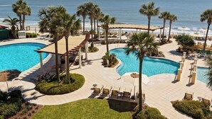 A resort with multiple swimming pools, palm trees, and a beach view. - Beautiful, First Floor South Villa at King & Prince with Resort Amenities (St Simons Island)