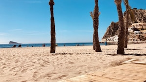 A beach with palm trees, a wooden walkway, and buildings in the background. - Luxury Apartment with pool by Poniente beach (Benidorm)
