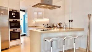 A modern kitchen with a central island, stainless steel appliances, and a bar area with stools. - Luxury Apartment with pool by Poniente beach (Benidorm)