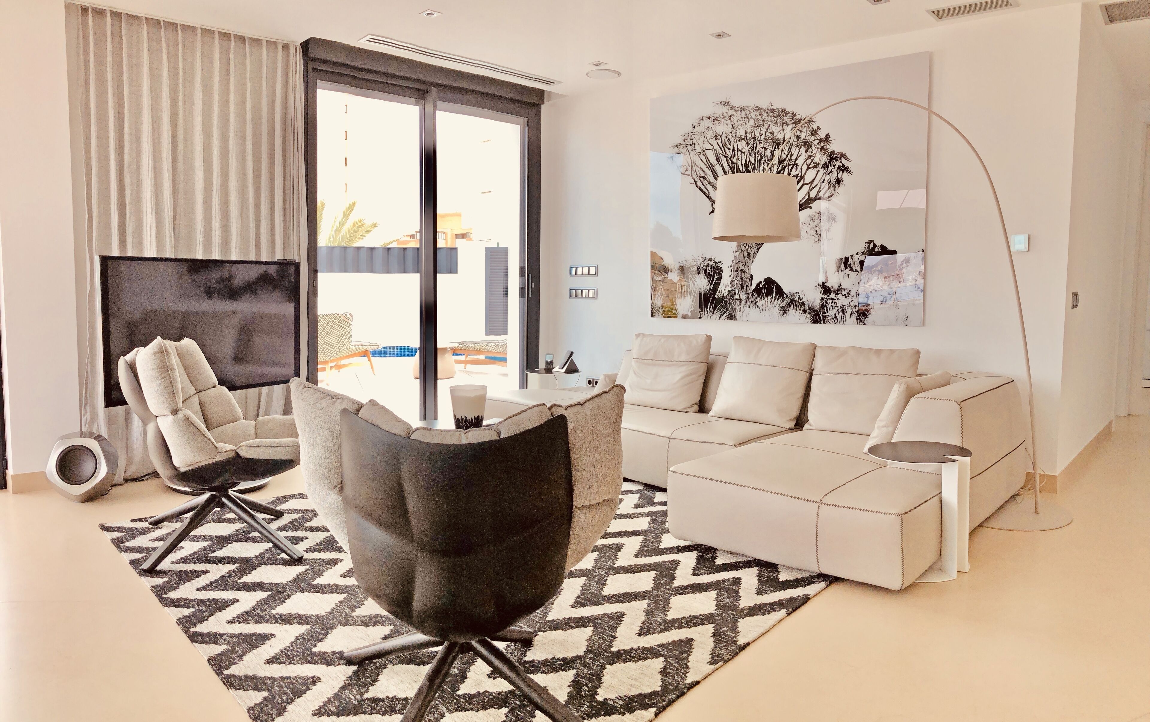 Un salon moderne avec un canapé, un fauteuil et un grand téléviseur à écran plat.