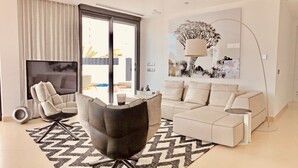 A modern living room with a sofa, armchair, and a large flat-screen TV. - Luxury Apartment with pool by Poniente beach (Benidorm)