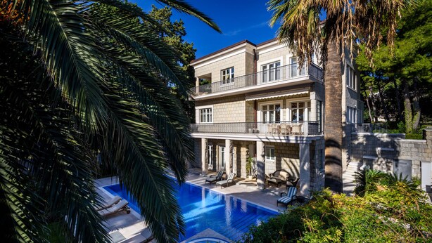 A two-story house with a swimming pool, surrounded by lush greenery and palm trees. - Villa Diocletian (Split)
