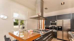 A modern kitchen with a central island, stainless steel appliances, and a large window with a view. - Villa Diocletian (Split)