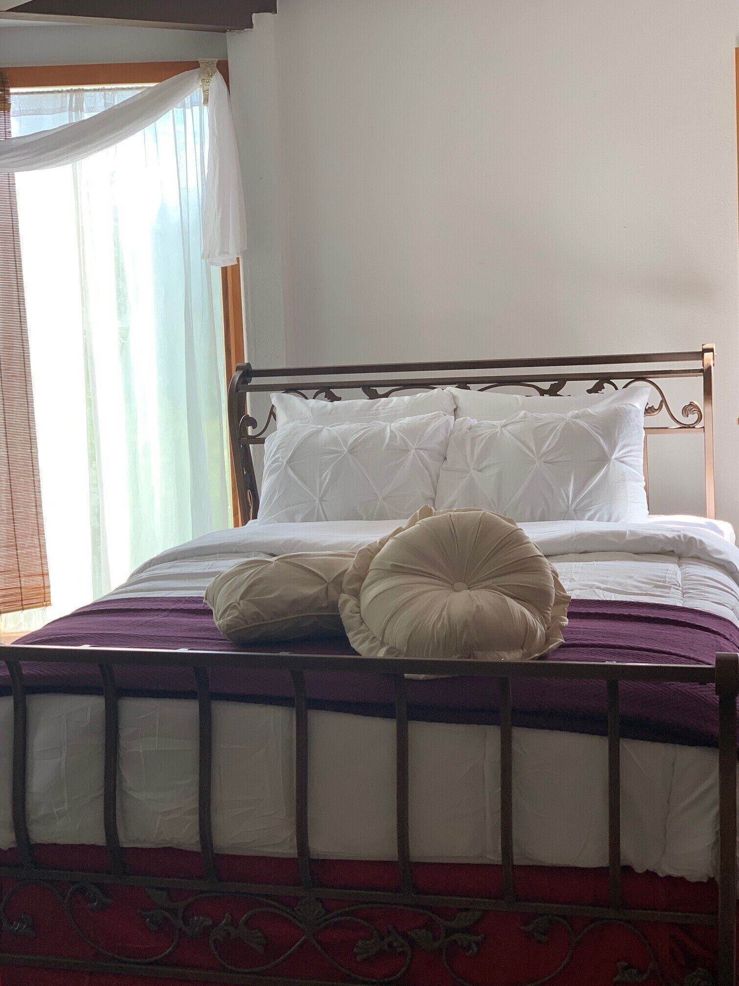 Ein Bett mit Metallgestell, weißer Bettwäsche und einer violetten Decke.