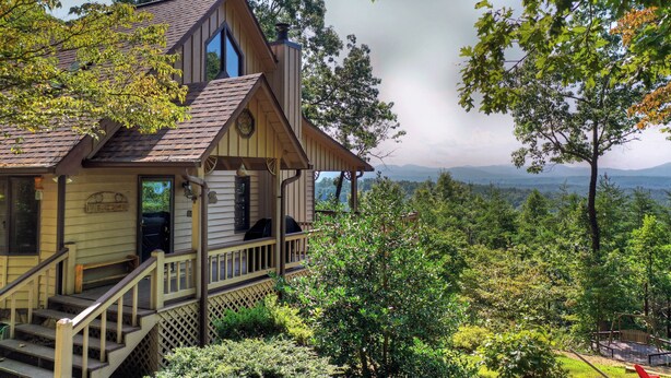 Une cabane en bois dotée d’un porche, d’une terrasse et offrant une vue panoramique sur les montagnes.