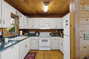 A kitchen with white cabinets, a microwave, a stove, and a refrigerator.