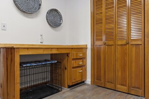 A wooden cabinet with a black metal cage, a wooden countertop, and a wooden door with louvered panels.