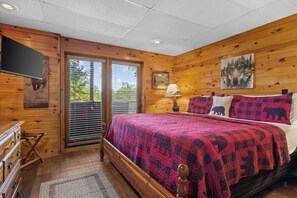A wooden cabin bedroom with a bed, a dresser, a lamp, and a painting on the wall. - Top of Mountain Views, Pet Friendly, Fenced Yard (Morganton)