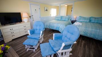 Un dormitorio con dos camas, televisión, cómoda y mecedoras.