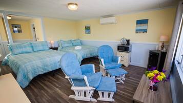 A room with two beds, a desk, a TV, and a window with curtains.