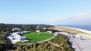 Vue aérienne d’une propriété située sur la côte, avec une grande pelouse, plusieurs bâtiments et une plage en arrière-plan.