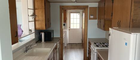 A kitchen with wooden cabinets, a white refrigerator, a stove, and a microwave.