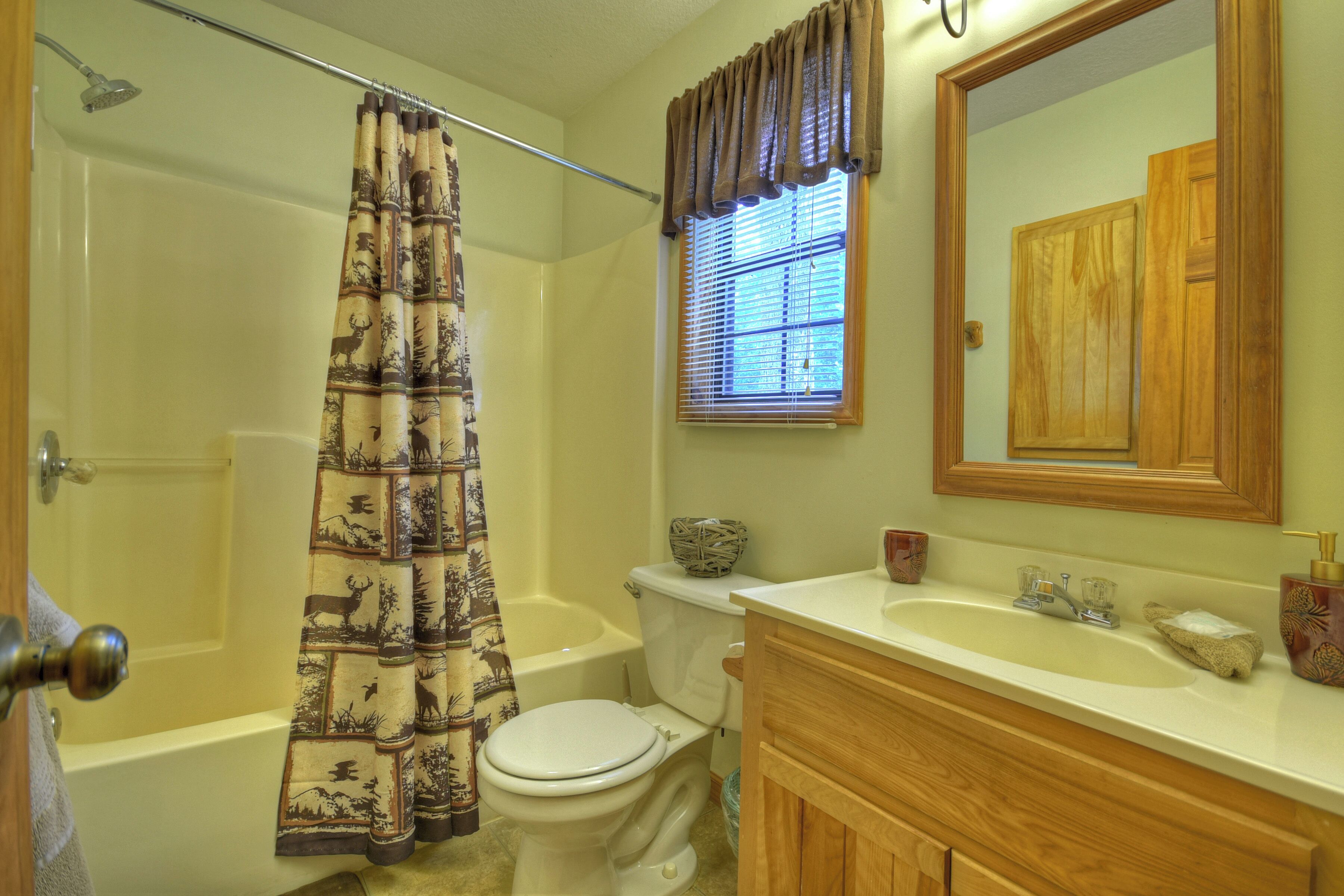 A bathroom with a shower, toilet, sink, and vanity.