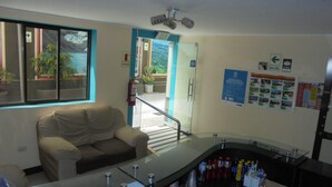 Rebedor d'hotel amb un sofà, una taula de recepció, una partició de vidre i vista cap a l'exterior.