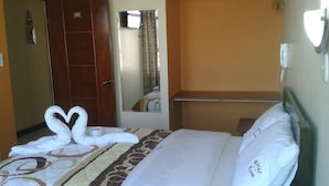 Habitació d'hotel amb llit, armari, mirall i tovalloles disposades sobre el llit.