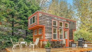 A cabin with a deck, outdoor seating, and a barbecue grill. - Fun Lofted Waterfront Home w/ Sauna and BBQ (Longview)