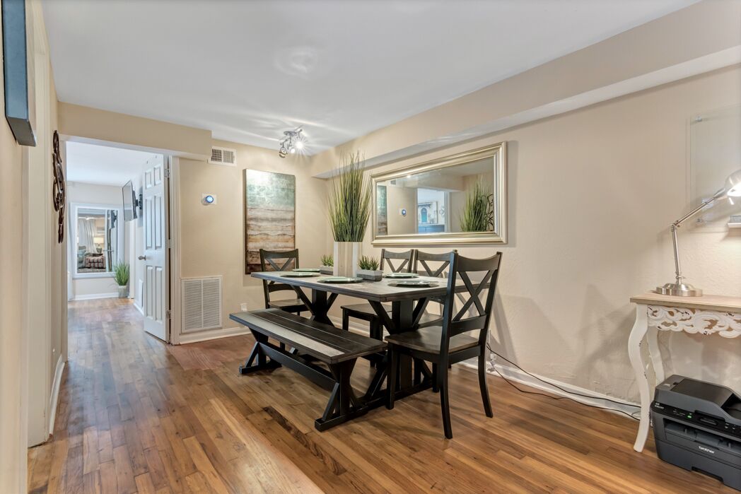 A dining area with a wooden table and chairs, a bench, a large mirror, and a printer on a small table.