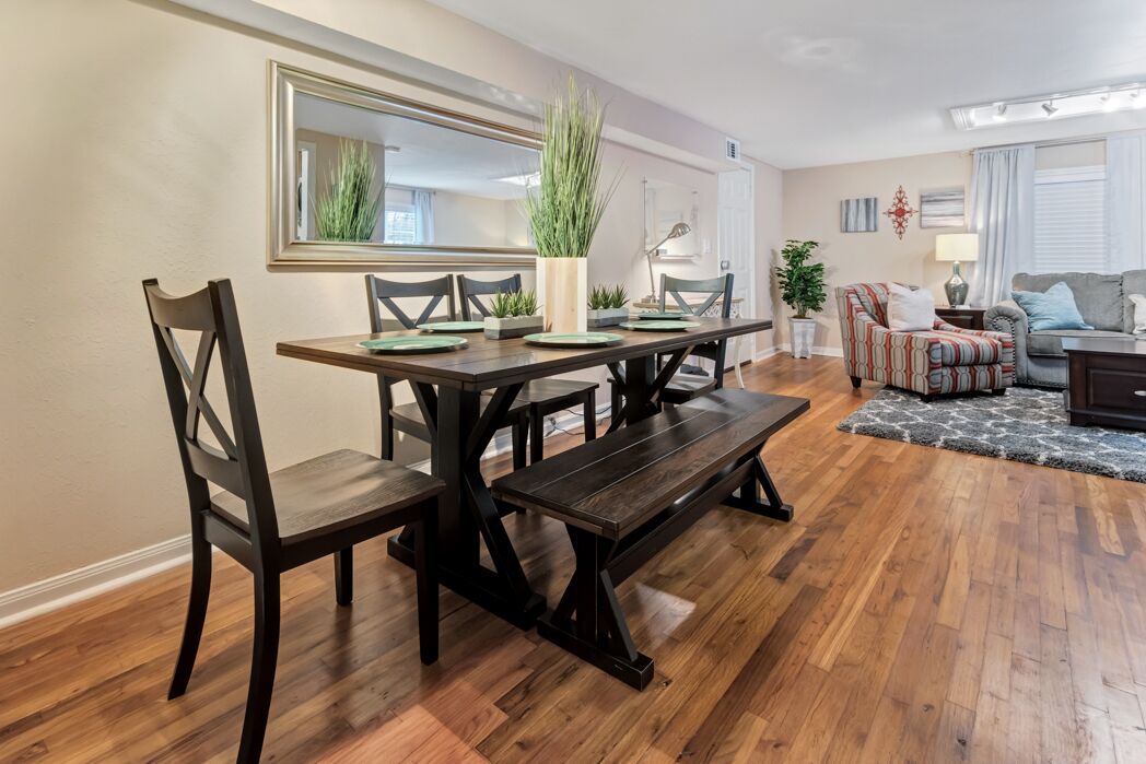 A dining area with a wooden table and chairs, a bench, and a potted plant.