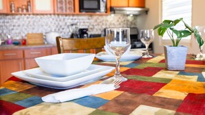 A dining table with a colorful quilt tablecloth, white plates, a wine glass, and a potted plant. - Colinas del Atlantico for 18 People (Isabela)