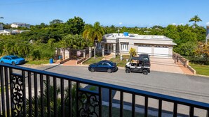 A residential property with a gated driveway, a two-story building, and a view of the surrounding greenery and other houses. - Colinas del Atlantico for 18 People (Isabela)