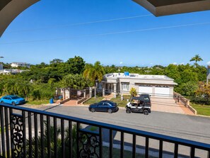 A residential property with a gated driveway, a two-story building, and a view of the surrounding greenery and other houses. - Colinas del Atlantico for 18 People (Isabela)
