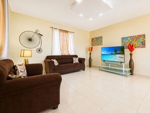 A living room with a brown sofa, a TV, and decorative wall art. - Colinas del Atlantico for 18 People (Isabela)