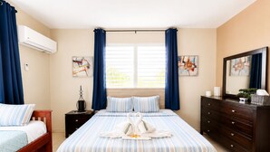 A hotel room with a large bed, a dresser, a nightstand, and a window with curtains. - Colinas del Atlantico for 18 People (Isabela)