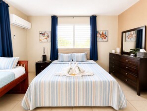 A hotel room with a large bed, a dresser, a nightstand, and a window with curtains. - Colinas del Atlantico for 18 People (Isabela)