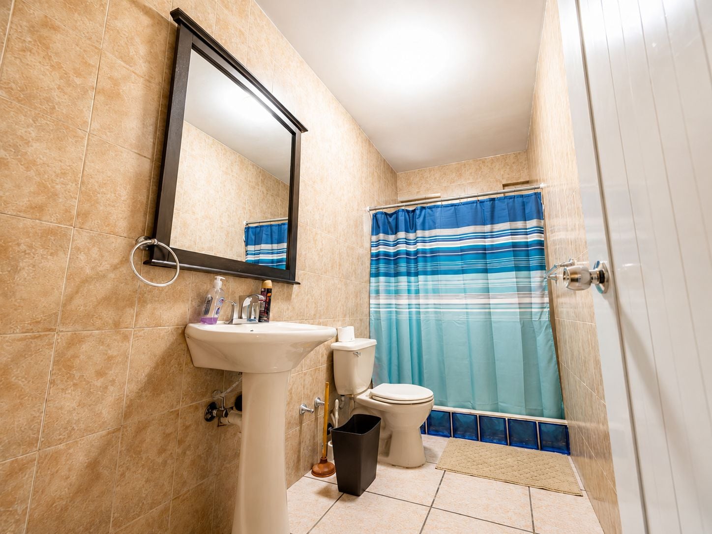 Un bagno con lavandino, WC e tenda per la doccia.