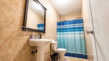 Un bagno con lavandino, WC e tenda per la doccia.