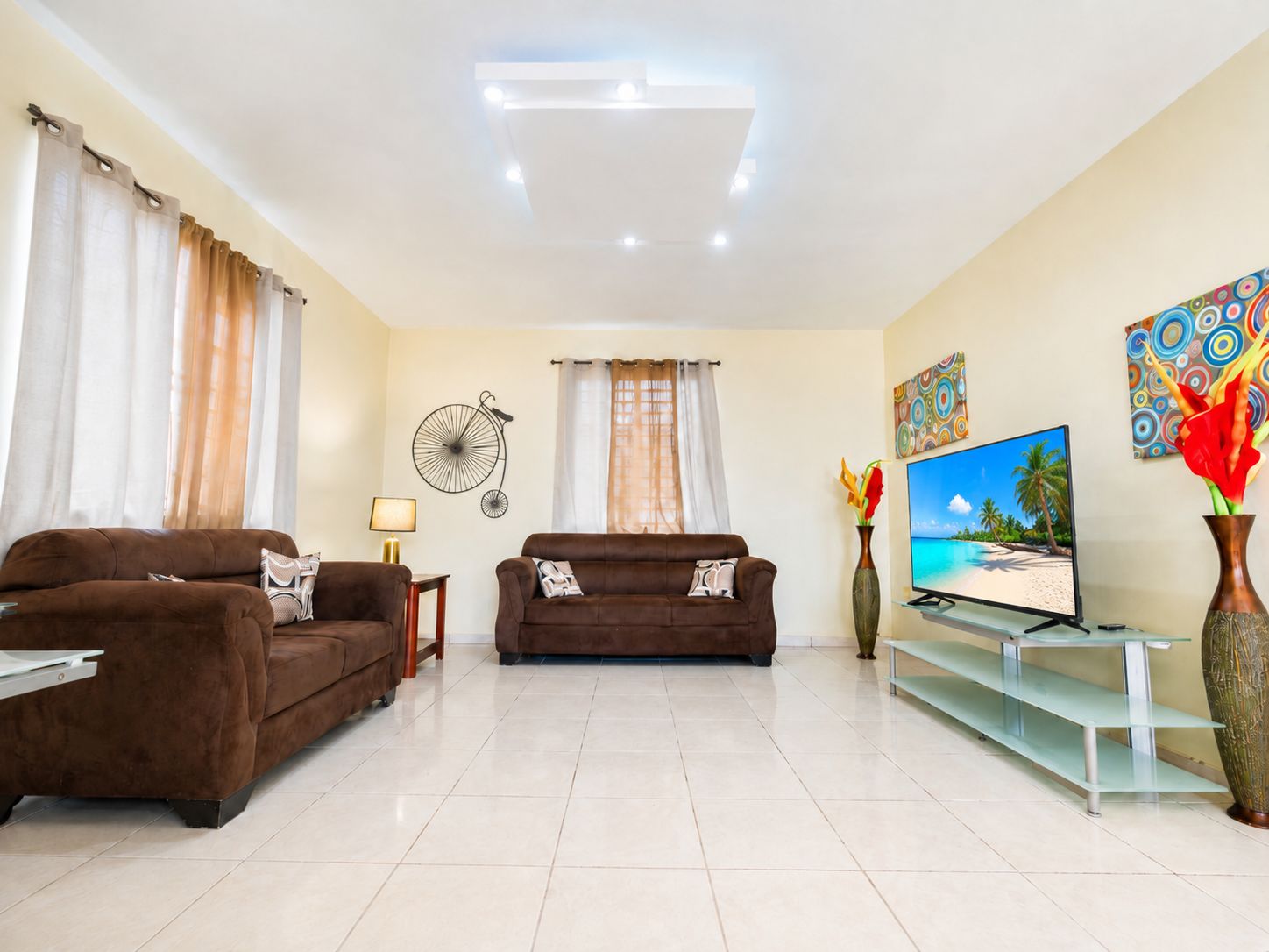 A living room with two brown sofas, a TV, and a wall-mounted fan.