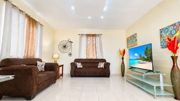 A living room with two brown sofas, a TV, and a wall-mounted fan.