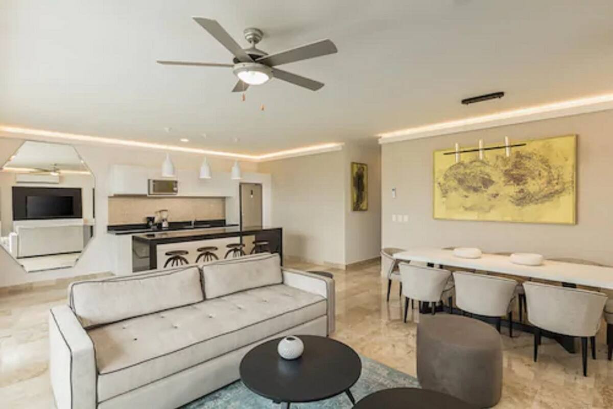 A modern living room with a sofa, a coffee table, and a dining area with chairs.