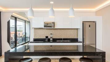 Una cocina moderna con una isla central, tres luces colgantes y un refrigerador de acero inoxidable.