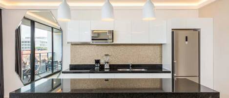 A modern kitchen with a black countertop, white cabinets, and three pendant lights.