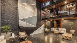 A modern lobby with a marble reception desk, seating area, and a staircase leading to upper floors. - Serenity Hotel Boutique by Alsol (Playa del Carmen)