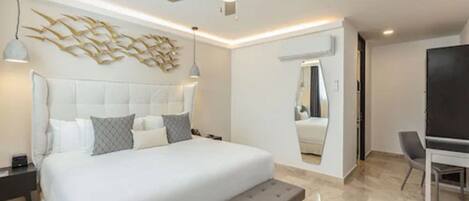 A modern bedroom with a large bed, a ceiling fan, and a wall-mounted mirror.