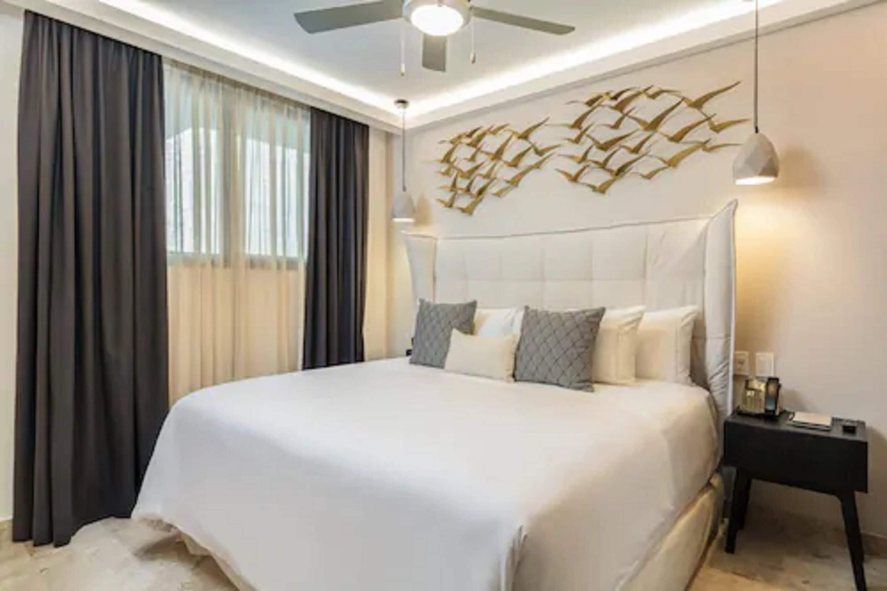 Una habitación de hotel moderna con una cama grande, un ventilador de techo y un adorno de pared decorativo.