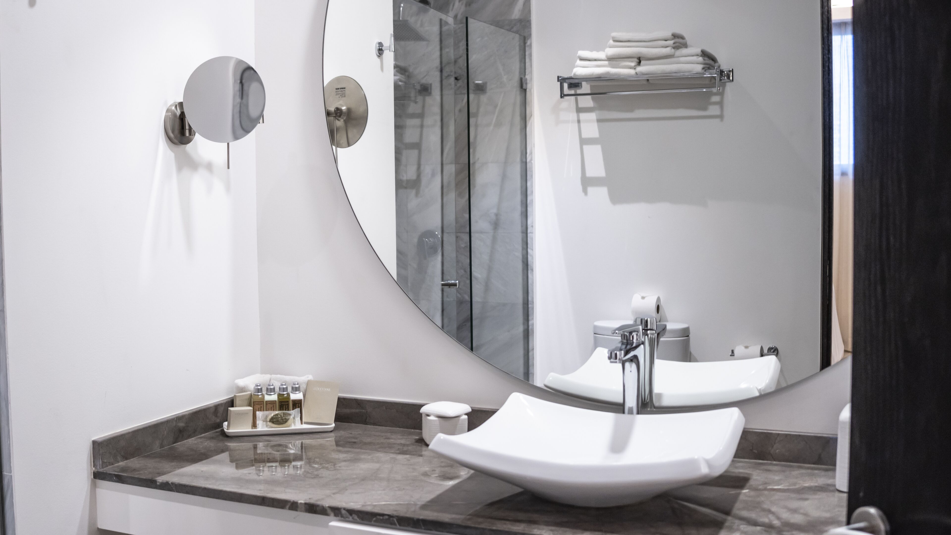 Un baño moderno con un espejo grande, un lavamanos y una cabina de ducha de vidrio.